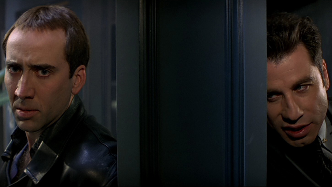 Nicholas Cage y John Travolta de pie en lados opuestos de una puerta sosteniendo armas en Face/Off.