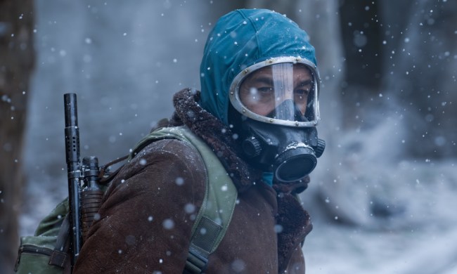 A man with a mask on stands in the snow.
